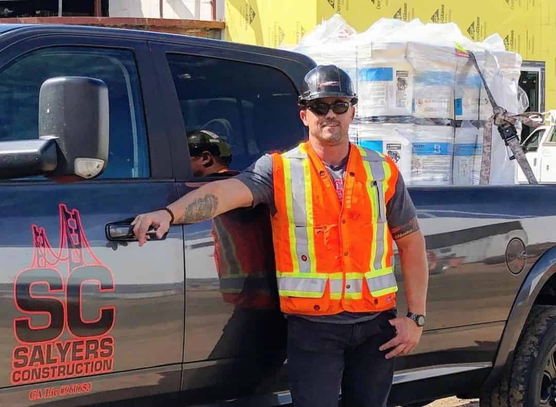 Salyers Construction team member on site beside the company truck and a pallet of materials.