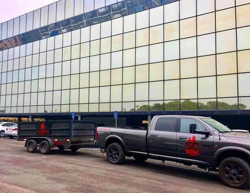 Salyers Construction truck and trailer at a glass-clad commercial building during a structural retrofit