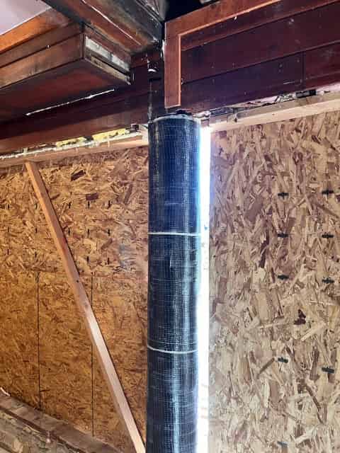 Carbon fiber fabric bonded to a structural beam beneath a wood subfloor.