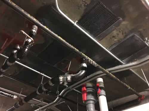Carbon FRP strips bonded to a concrete slab underside, routed around overhead piping.