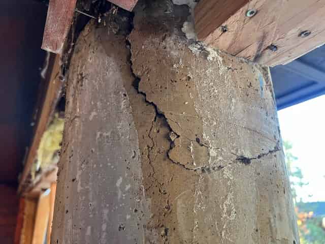 Concrete column with surface spalling exposed for preparation before strengthening.