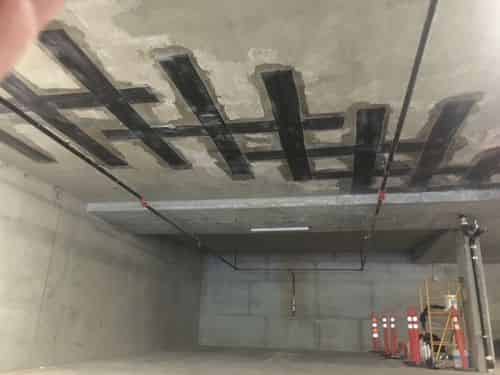 Externally bonded carbon FRP strips applied to a concrete deck during a Tyfo-system seismic retrofit.